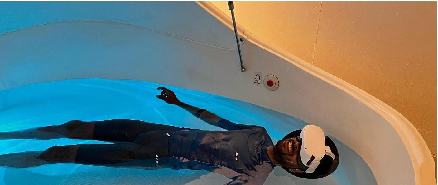 A participant floating in the tank wearing a headset. Real water for the body, virtual water for the head.