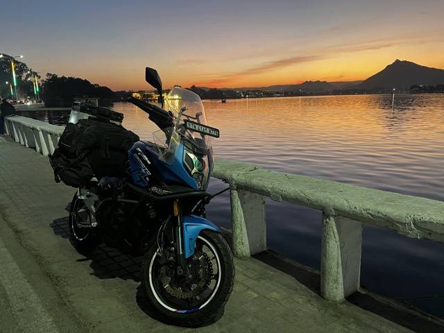 Sunset over a lake in Rajasthan, with the bike parked on the causeway.